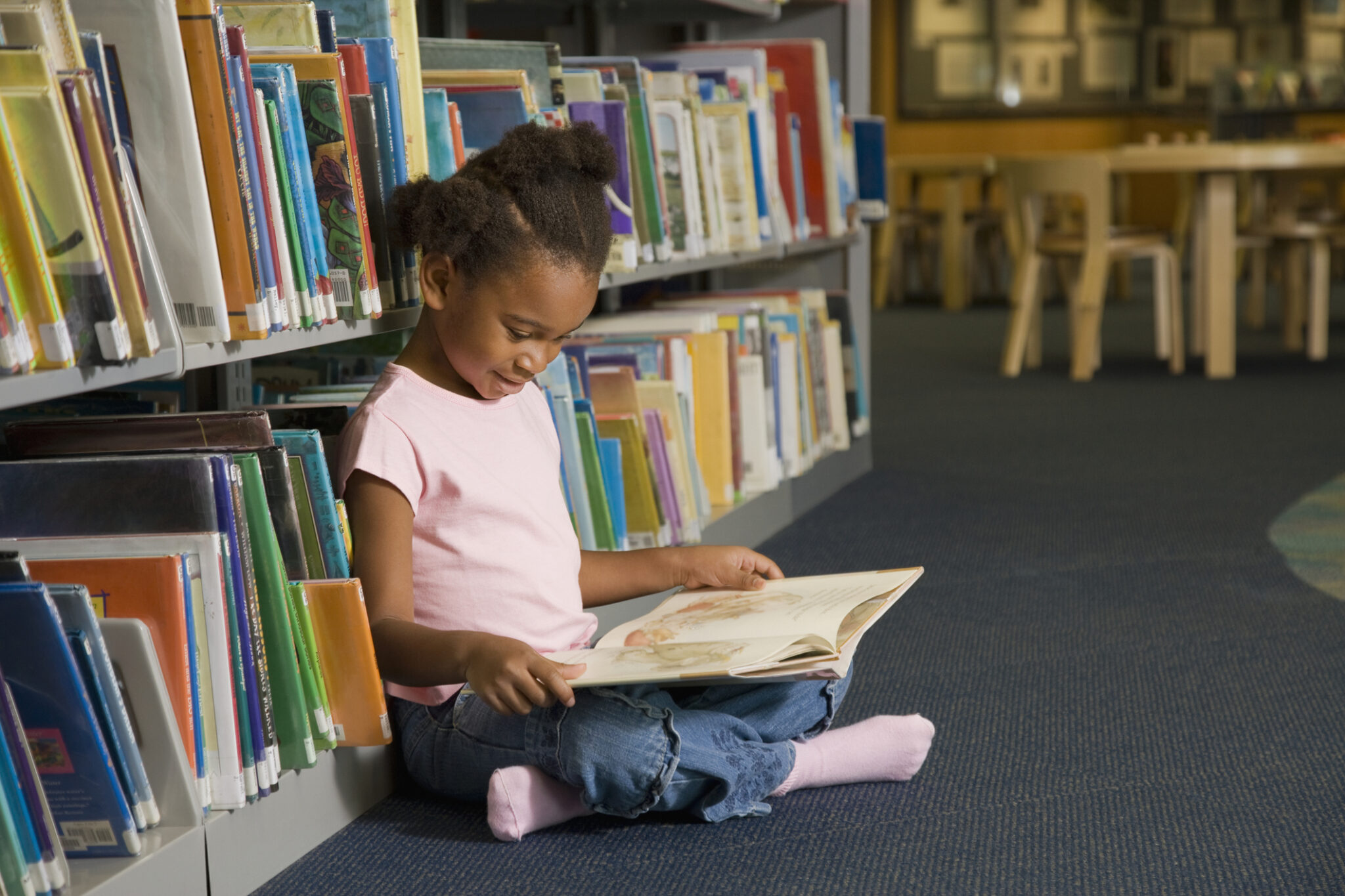 African girl reading library book